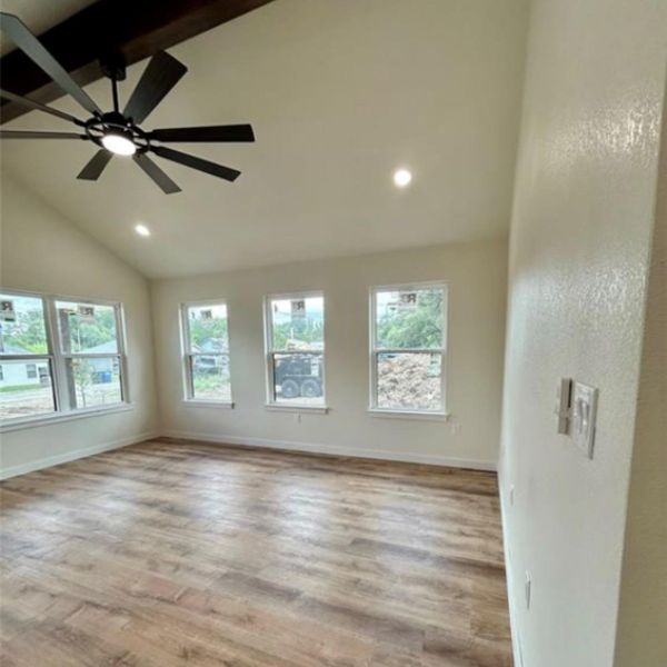 Laminate flooring and vaulted ceilings create an open, airy ambiance in this well-lit living space.