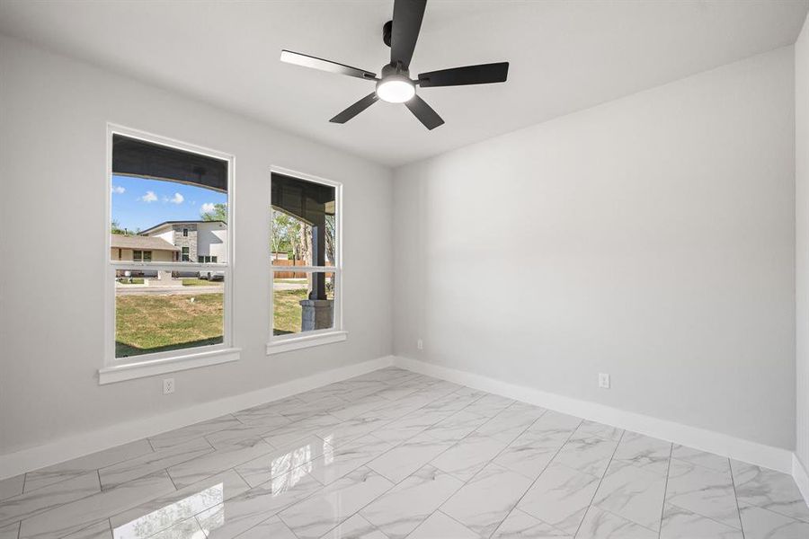 Empty room featuring light marble finish flooring and ceiling fan