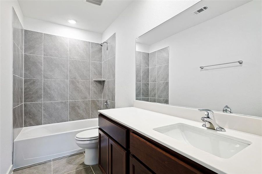 Bathroom featuring vanity, shower / tub combination, and dark tile patterned floors