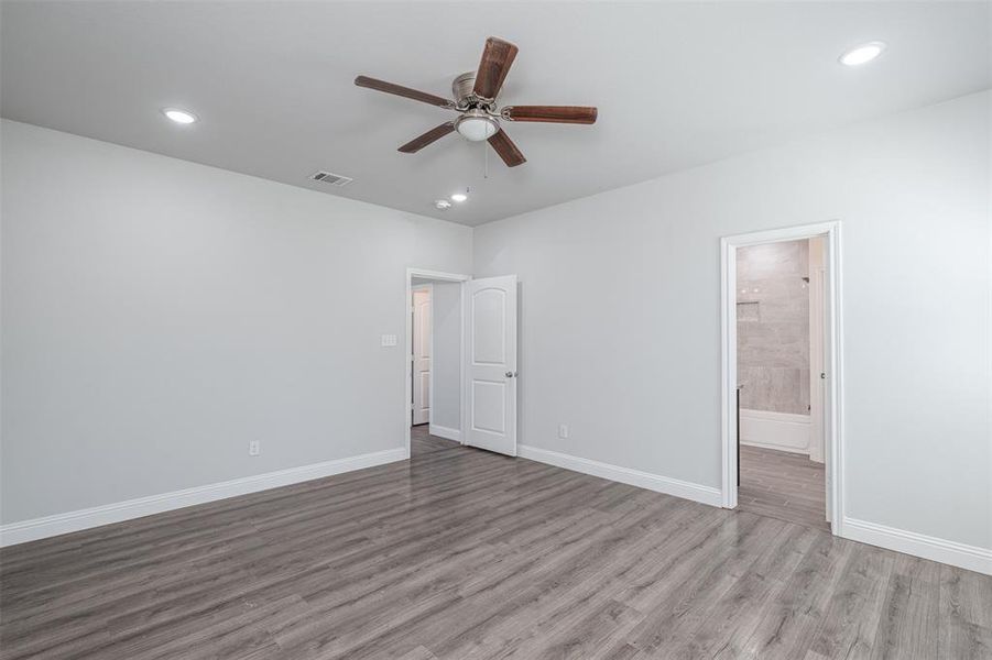 Unfurnished bedroom with visible vents, baseboards, ensuite bath, light wood-style flooring, and recessed lighting