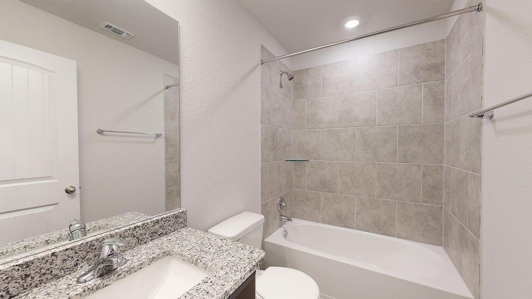 Bathroom featuring shower / washtub combination, vanity, and a textured wall Bathroom featuring shower / washtub combination, vanity, and a textured wall