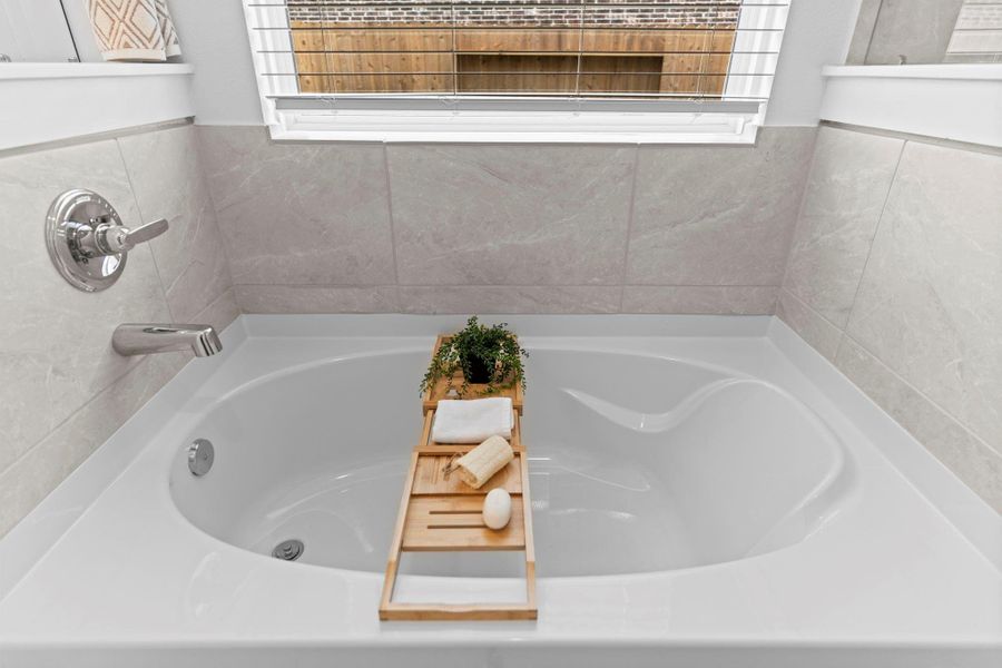A closer look at the soaking tub reveals beautiful tilework, a picture window for natural light, and space to unwind in style. **Image Representative of Plan Only and May Vary as Built**.