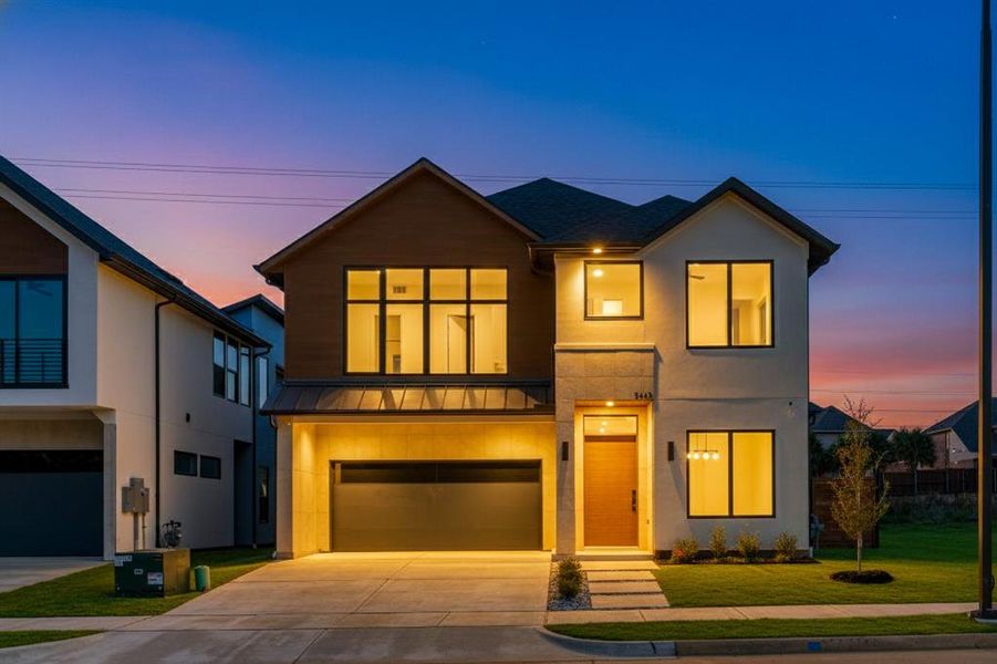 Contemporary house featuring a front lawn, driveway, a metal roof, a standing seam roof, and a garage Contemporary house featuring a front lawn, driveway, a metal roof, a standing seam roof, and a garage