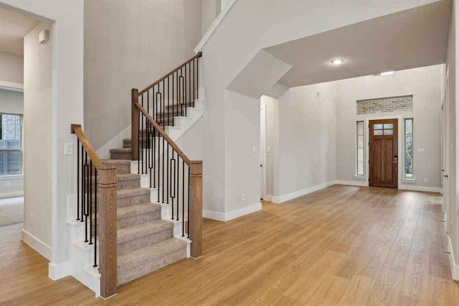 Foyer entrance featuring wood finished floors, healthy amount of natural light, stairs, and a high ceiling