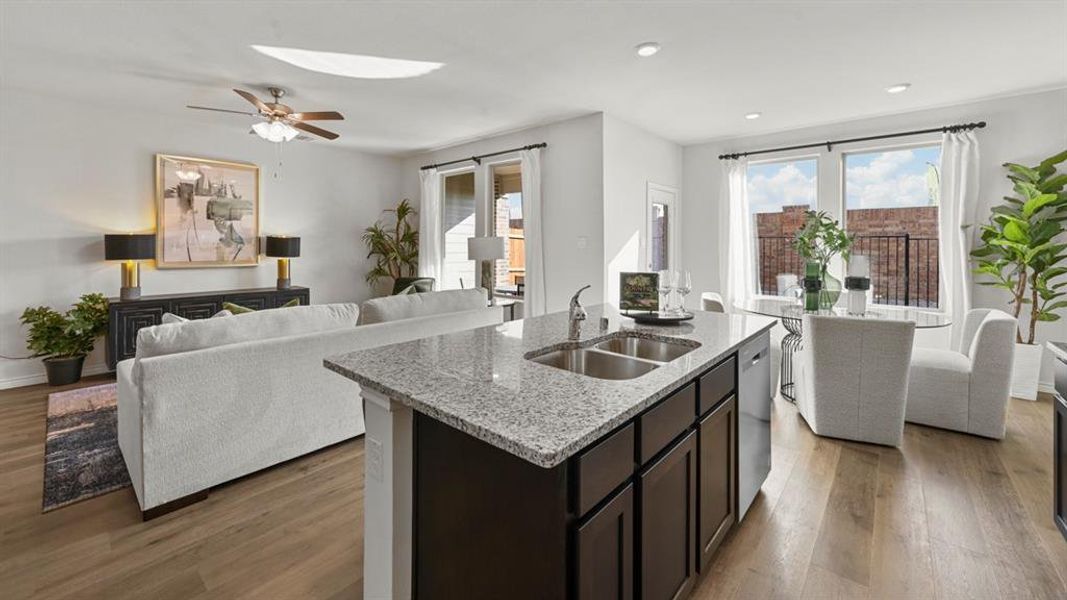 Kitchen with open floor plan, dark wood-type flooring, light stone countertops, a skylight, and an island with sink