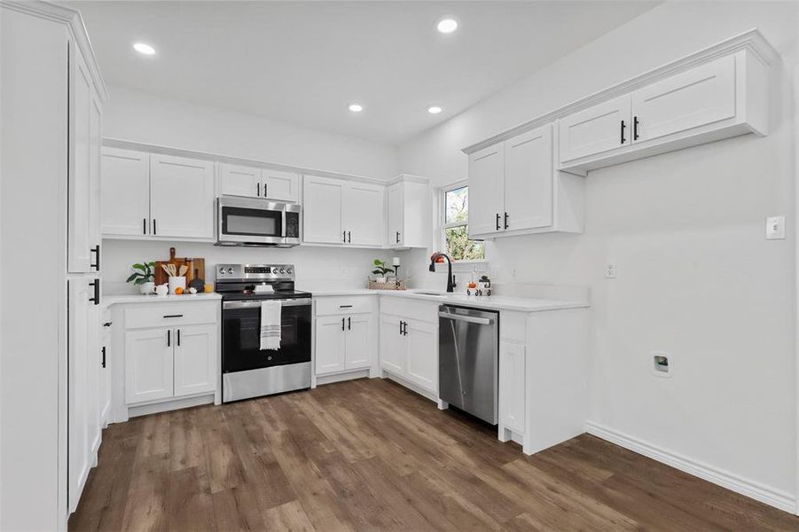 Kitchen featuring sink, dark wood-type flooring, white cabinetry, and stainless steel appliances