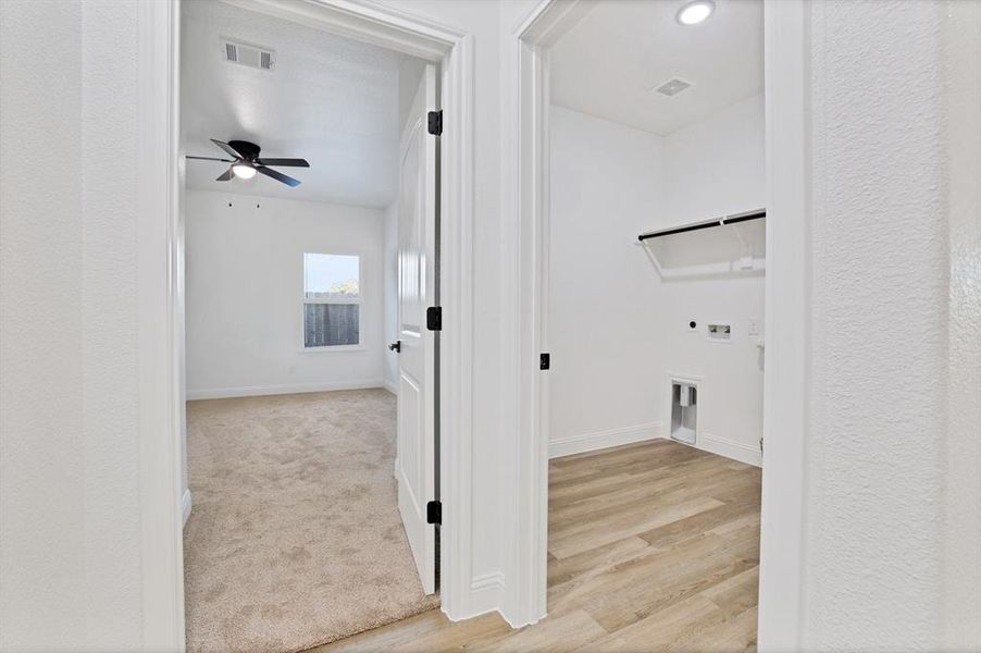 Washroom with electric dryer hookup, ceiling fan, light hardwood / wood-style flooring, and washer hookup