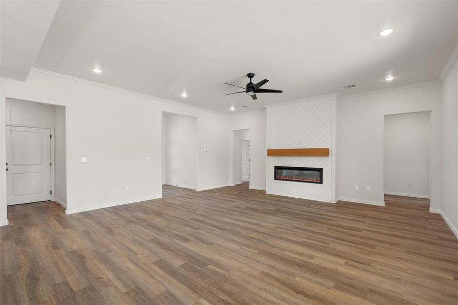Unfurnished living room featuring a fireplace, wood finished floors, ornamental molding, ceiling fan, and recessed lighting Unfurnished living room featuring a fireplace, wood finished floors, ornamental molding, ceiling fan, and recessed lighting