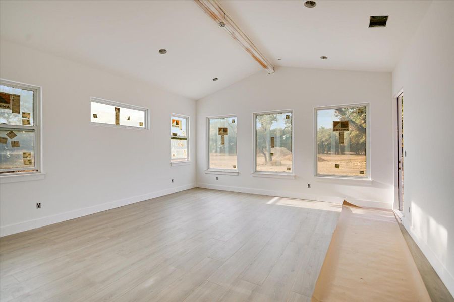 Spare room with vaulted beamed ceiling, baseboards and light wood-style floors