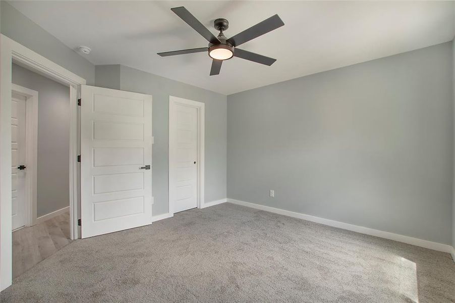 Unfurnished bedroom with light colored carpet and ceiling fan