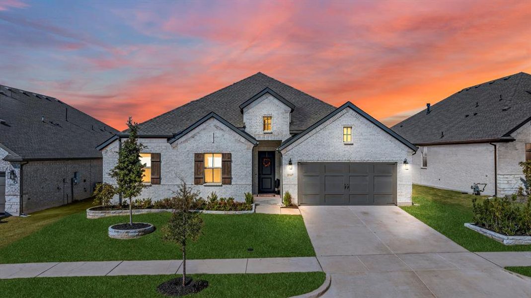 French country style house with driveway, brick siding, a yard, and a shingled roof