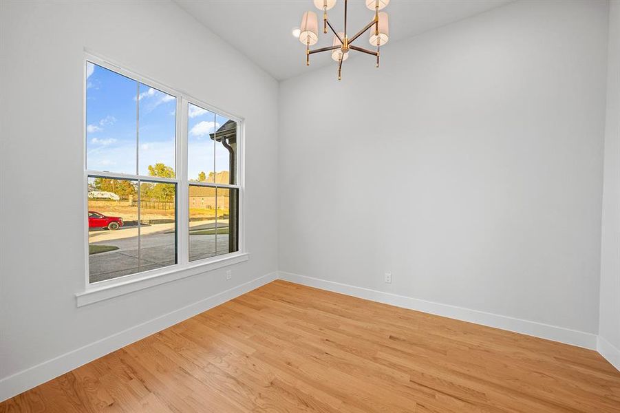 Unfurnished room featuring a chandelier and light wood-style flooring Unfurnished room featuring a chandelier and light wood-style flooring
