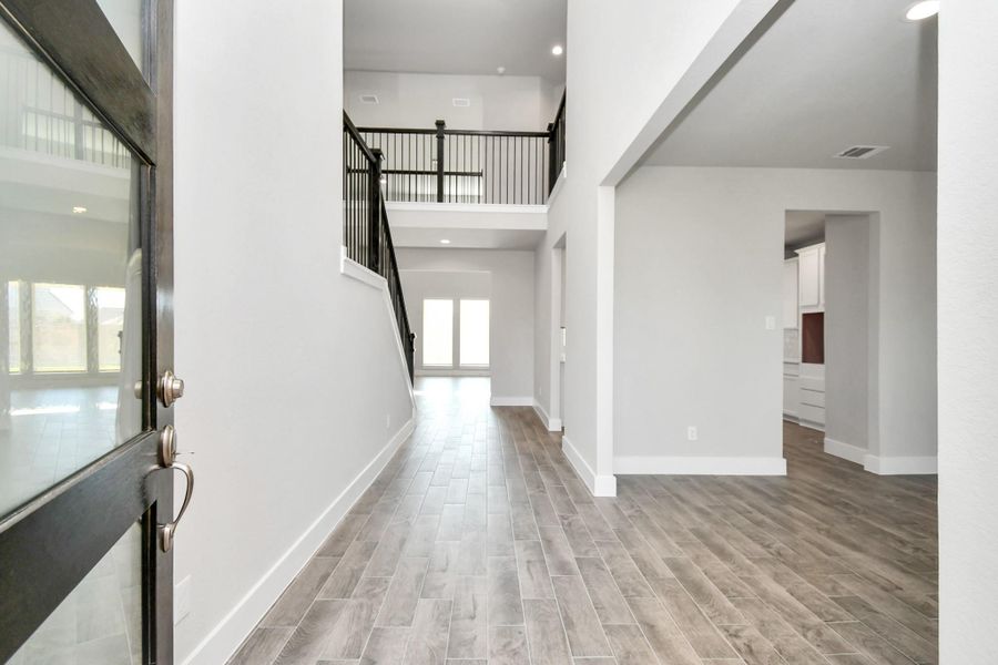 As you step into the threshold of this luxurious home, you'll soon be welcomed by an elegant glass door (to be installed). Inside, soaring ceilings amplify the spaciousness, while the refined wood-look tile flooring and oversized baseboards exude sophistication and charm. Sample photo of completed home with similar floor plan. Actual colors and selections may vary.