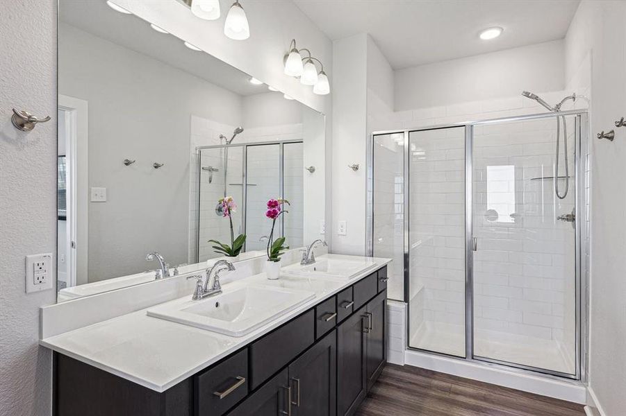 Bathroom featuring vanity, a shower with door, and dual sinks