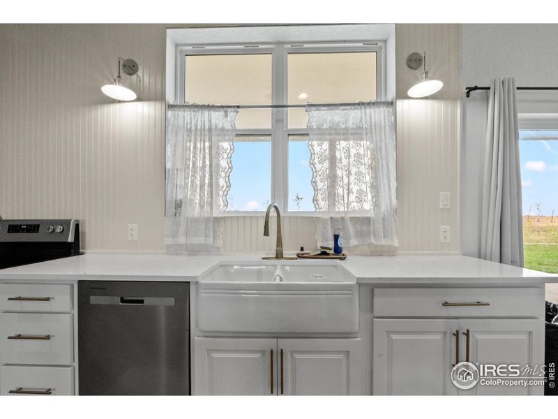 Charming farmhouse-style apron sink with country views accented by sleek fixtures