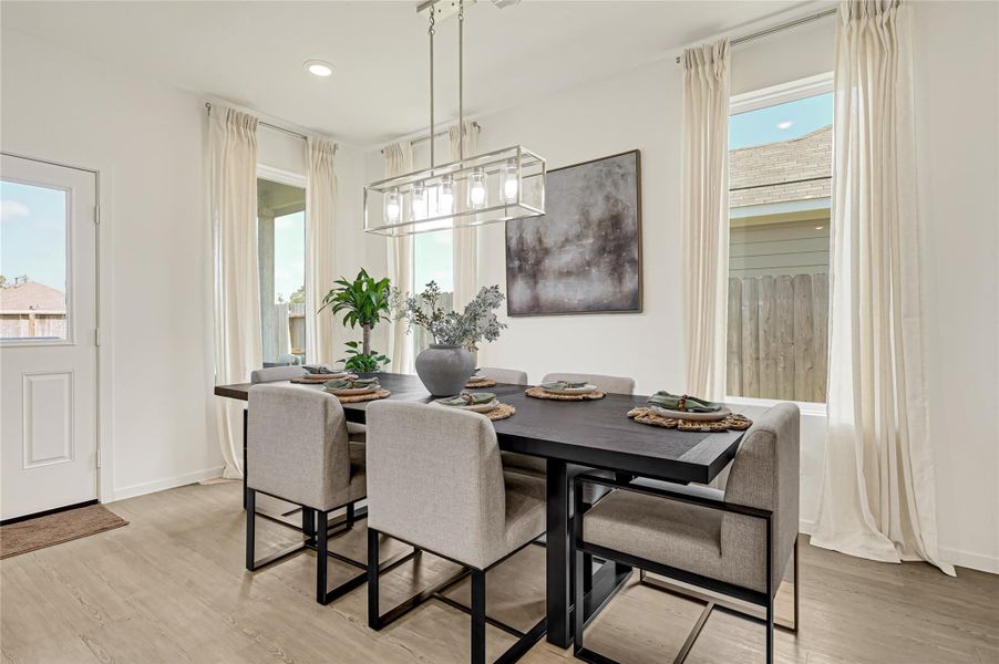Bright and inviting dining area featuring a sleek black table, modern light fixture, and large windows with sheer curtains, creating an elegant space for gatherings. Bright and inviting dining area featuring a sleek black table, modern light fixture, and large windows with sheer curtains, creating an elegant space for gatherings.