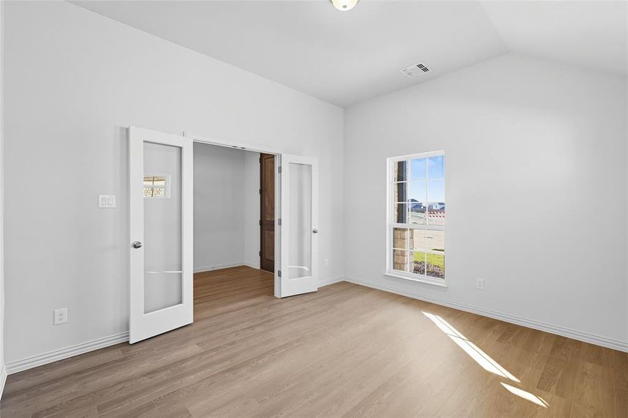 Unfurnished bedroom with light wood-style flooring and french doors Unfurnished bedroom with light wood-style flooring and french doors