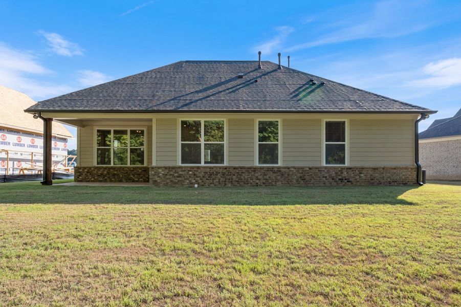 Rear exterior with tan siding and a dark shingle roof