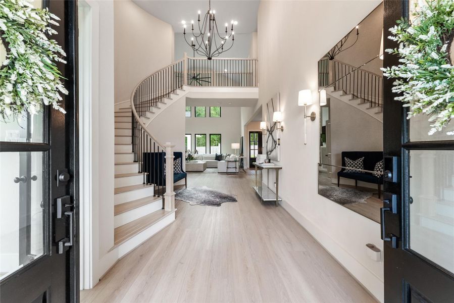 The foyer opens with impressive ceiling height, designer lighting, and immediate sight lines into the main living areas. Wide plank flooring and neutral finishes create a seamless flow from the moment you enter.