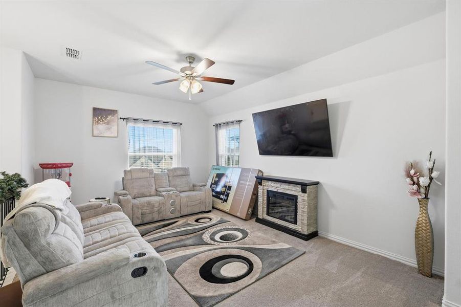 Living room with a fireplace, carpet flooring, and ceiling fan