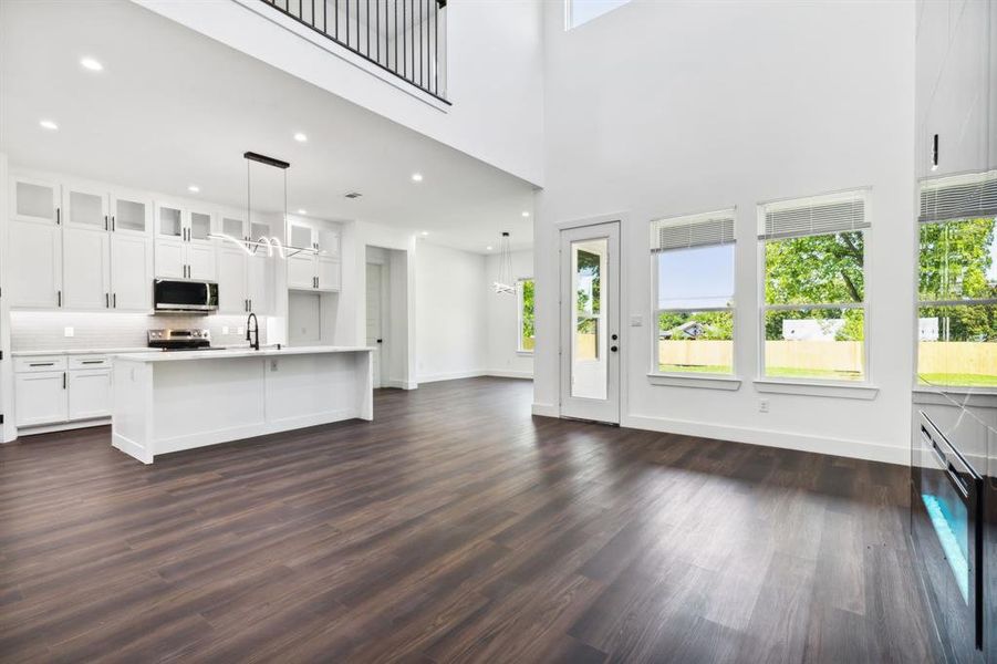 Kitchen with stainless steel appliances, pendant lighting, dark hardwood / wood-style floors, and white cabinetry