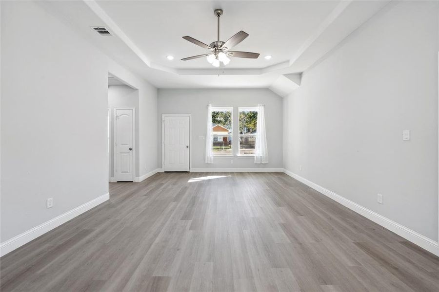 Spare room featuring light wood-type flooring, a raised ceiling, and ceiling fan