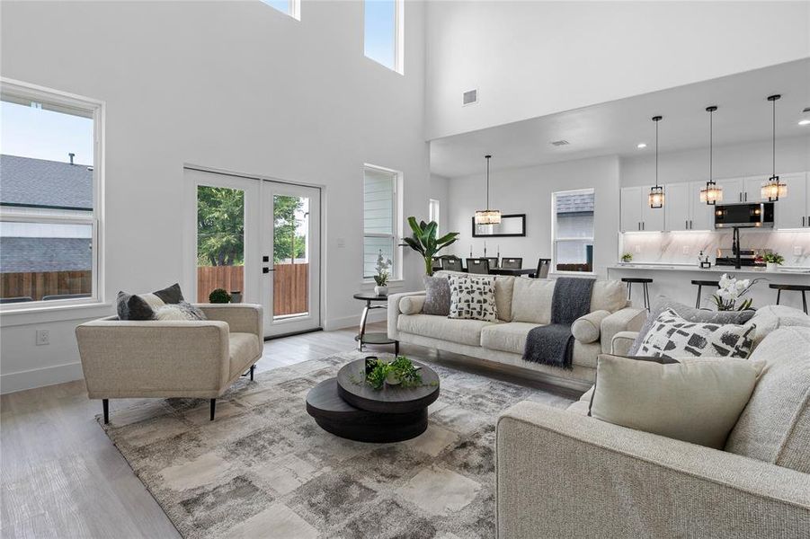 Living area featuring light wood-style flooring, a high ceiling, and french doors Living area featuring light wood-style flooring, a high ceiling, and french doors