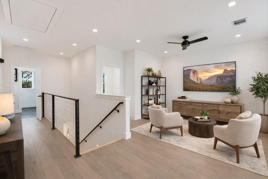 Staged Photo. Welcome to the ultimate East Side hangout. This versatile flex space can be used as a cozy media lounge or additional workspace. The sleek cable railing coming up the stairs maintains the home’s open, airy feel.