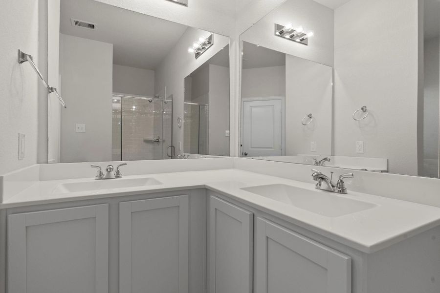 Dual vanities and expansive mirrors in the primary bath provide plenty of space for morning routines. The elegant cabinetry and clean design add a touch of sophistication to this private ensuite.