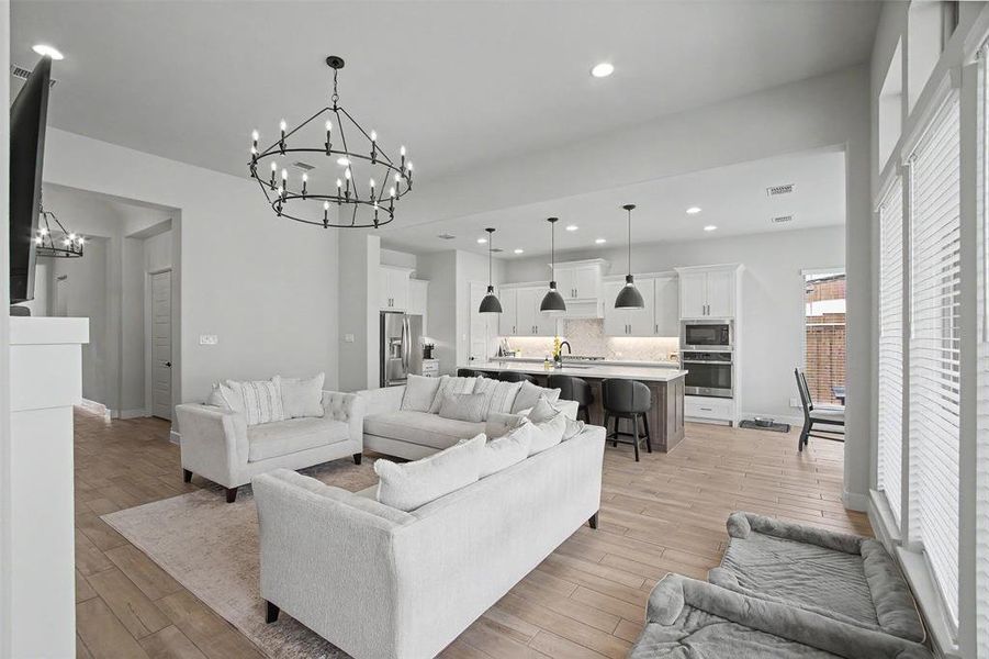Open-concept living area featuring wood-finish flooring and an ornate black chandelier