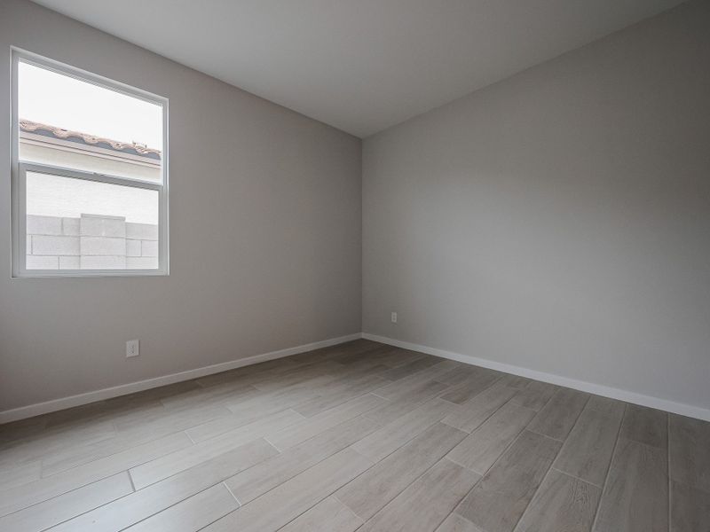 A room with a wood floor and a white wall with a painting on it.