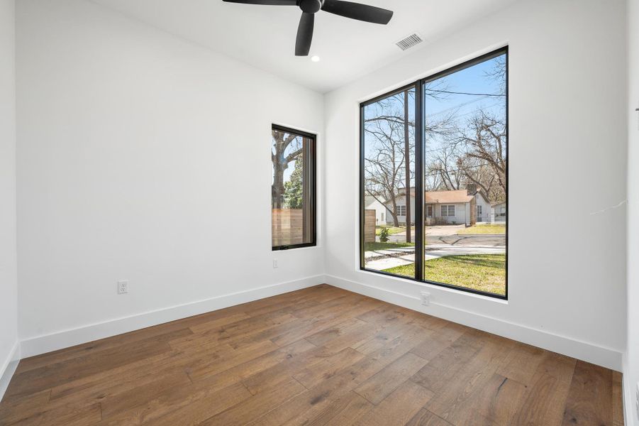 Unfurnished room with a wealth of natural light, visible vents, wood-type flooring, and baseboards