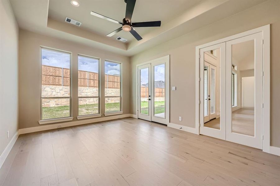 Spare room with french doors, light hardwood / wood-style flooring, a tray ceiling, and ceiling fan