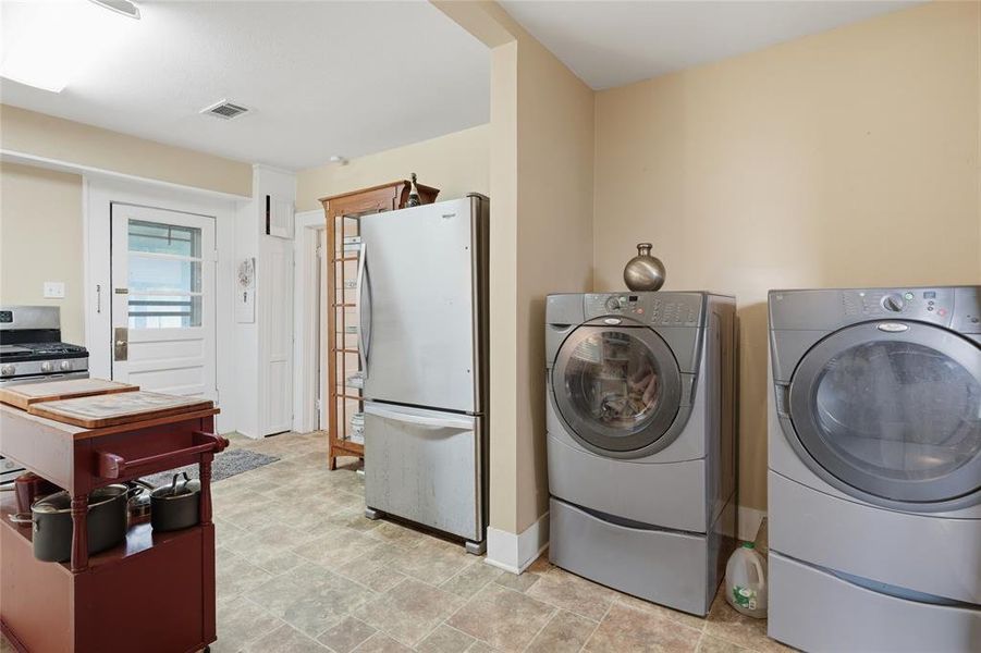 Utility area featuring a washer and dryer, tile flooring, a side-by-side refrigerator, and a white paneled door with glass insert