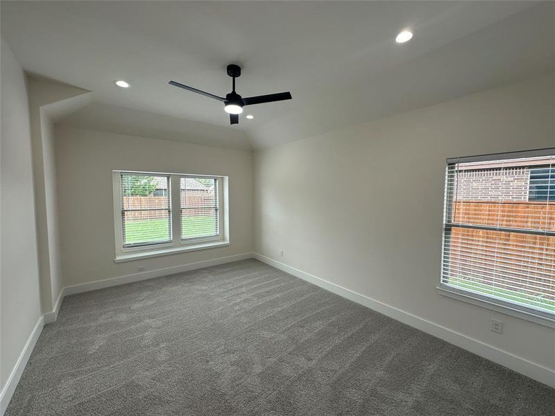 Carpeted spare room featuring ceiling fan and lofted ceiling