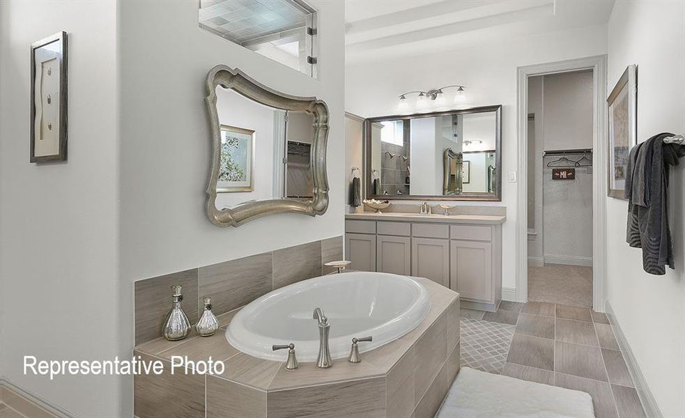 Soaking tub with tile surround, dual vanity with solid surface countertop, walk-in shower with tile surround, and tile flooring