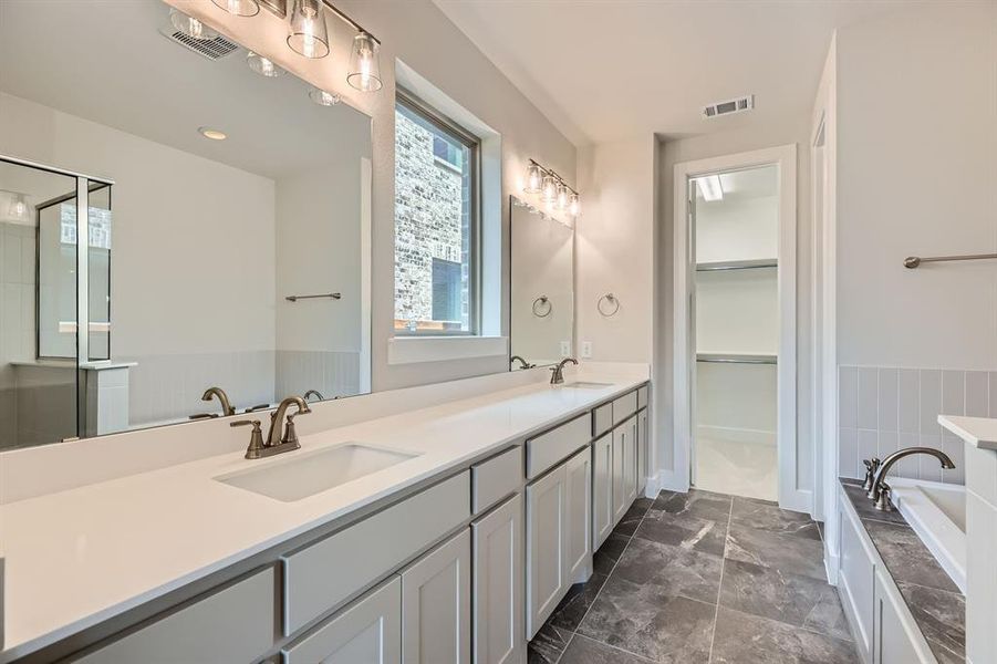 Bathroom featuring a bath, double vanity, a spacious closet, and a shower stall