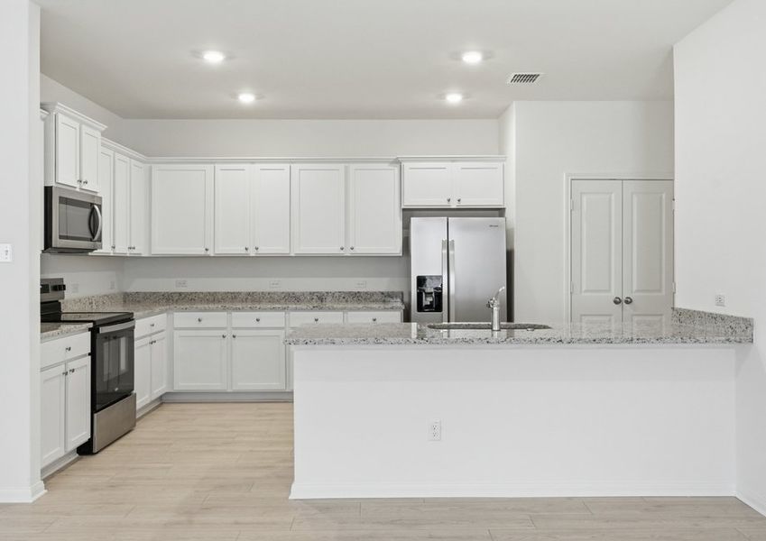 Kitchen featuring a granite island, white cabinetry, and a stainless steel range and microwave. Kitchen featuring a granite island, white cabinetry, and a stainless steel range and microwave.