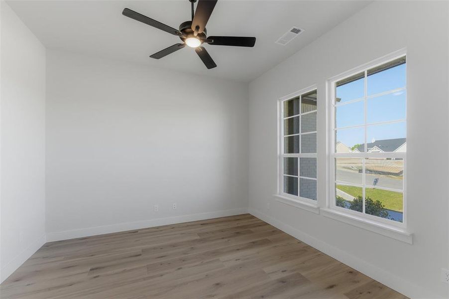 Empty room with ceiling fan and light wood-type flooring