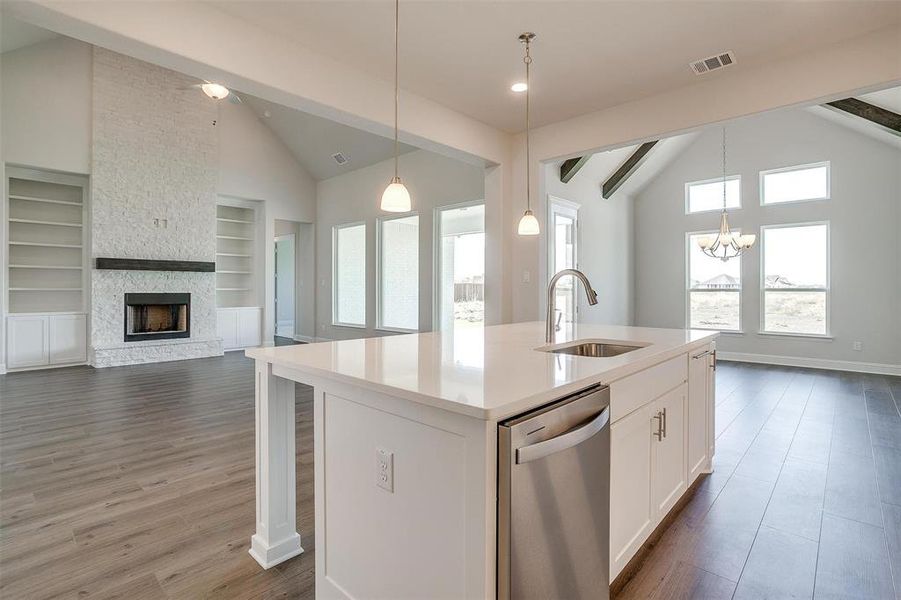 Kitchen featuring white cabinets, dishwasher, beamed ceiling, a kitchen island with sink, and sink