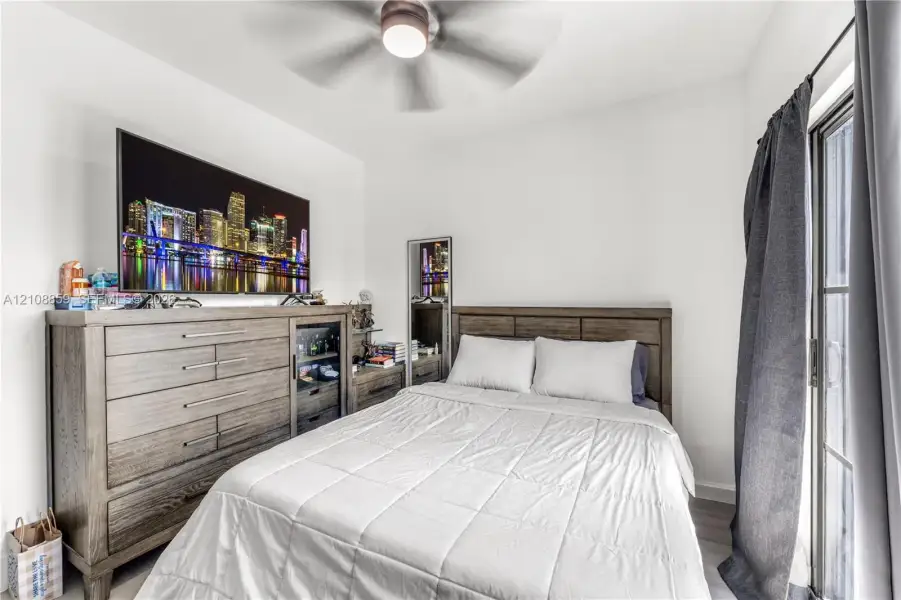 Bedroom featuring wood-finish flooring, a ceiling fan with integrated lighting, and a sliding glass door