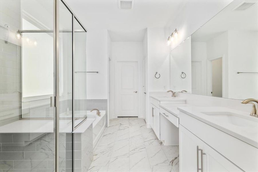 Spacious bathroom featuring a dual vanity with ample counter space, a large frameless mirror, a walk-in shower with a built-in bench, a separate soaking tub, and marble-look floor tiling