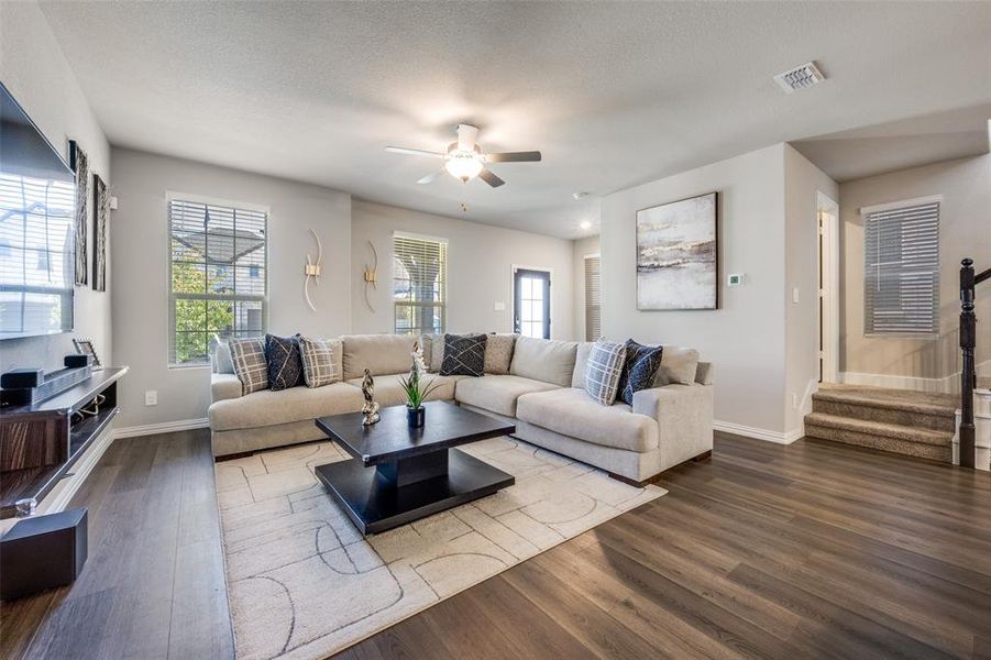 Living room with wood finished floors, stairway, ceiling fan, and a textured ceiling Living room with wood finished floors, stairway, ceiling fan, and a textured ceiling