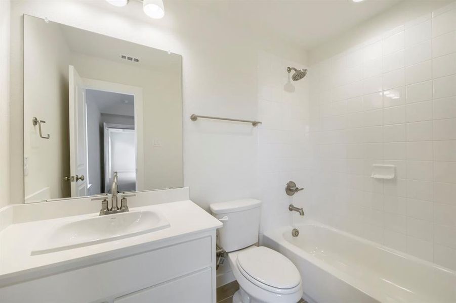 Full bathroom featuring a white tile tub/shower combination with a brushed nickel shower head and fixtures Full bathroom featuring a white tile tub/shower combination with a brushed nickel shower head and fixtures