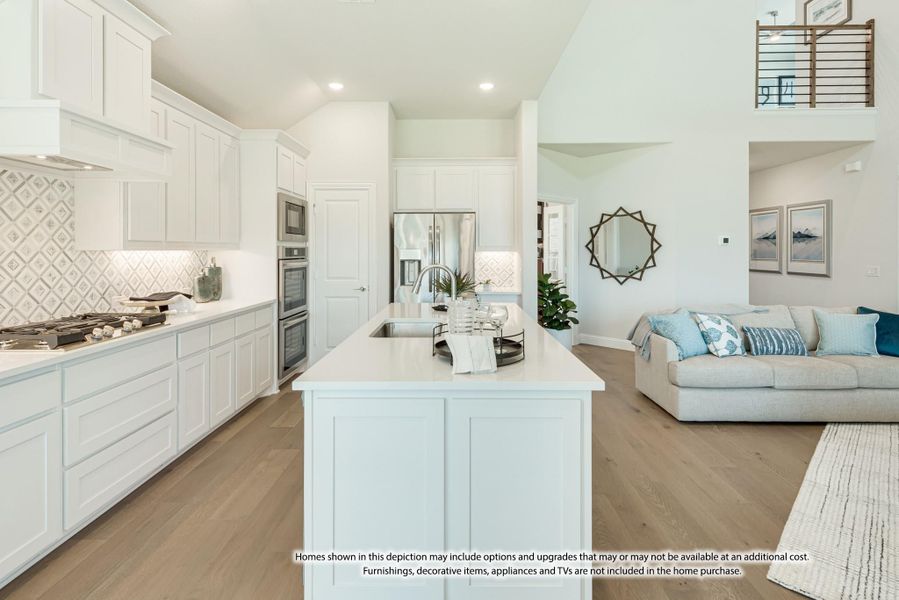 Open-concept kitchen with white cabinets, center island, and stainless appliances opening to living room with hardwood floors Open-concept kitchen with white cabinets, center island, and stainless appliances opening to living room with hardwood floors