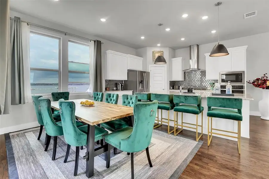Dining space with recessed lighting, dark wood-style floors, and a water view
