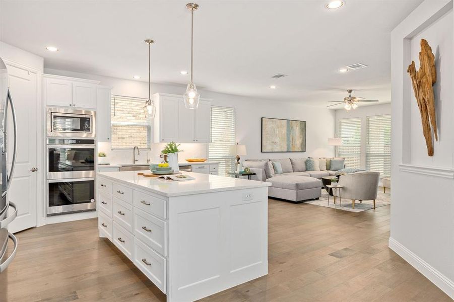 Kitchen with white cabinetry, large island, double ovens, gas cooktop and apron sink