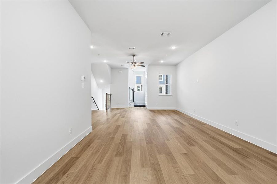 Living area featuring light wood flooring, white walls, and recessed lighting