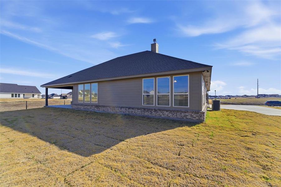 Back of house featuring a lawn, a chimney, a patio, and a shingled roof