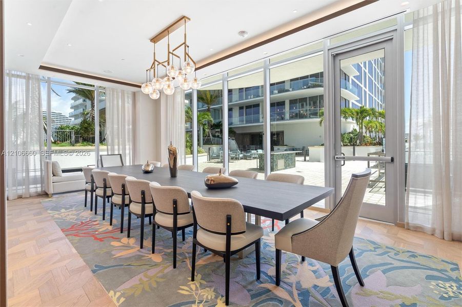 Floor-to-ceiling glass walls, herringbone-patterned wood-finish flooring, multi-light geometric chandelier, and recessed ceiling lighting